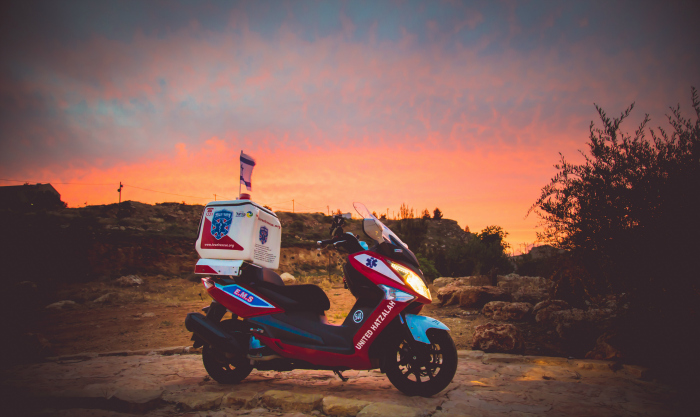 A United Hatzalah ambucycle with an Israeli flag in the background